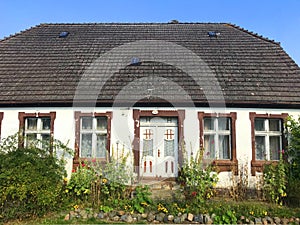 Facade of an old village house in Poland with overgrown front yard garden.