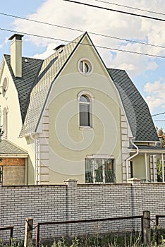 the facade of one gray large private house with white windows under a green tiled roof