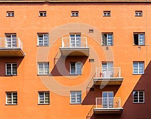 Facade of an orange building with its windows, balconys and shadows. photo