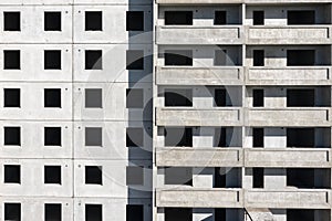 Facade of a panel multistory building under construction. Gray geometric background.