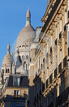 The facade of Parisian building and Sacre Coeur basilica in the background , France.