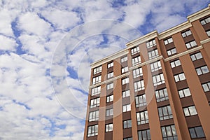 Facade part of modern residential apartment building against cloudy blue sky