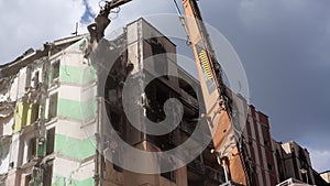 Facade of a residential abandoned multi-storey building after a strong fire. A construction excavator with a hydraulic