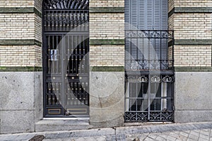 Facade of a residential building with granite blocks on the ashlars and black metal portal and bars on the windows photo