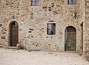 The facade of a rural stone farmhouse with wooden doors and windows in the italian countryside Tuscany, Italy