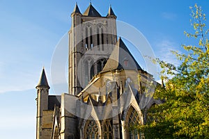 Facade of Saint Nicholas` Church Sint-Niklaaskerk in Ghent, Belgium, Europe, with green tree at the foreground during a sunny