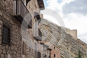 Facade with shield at the beginning of a street in AlbarracÃ­n, house with balconies, at the bottom part of the castle wall of the