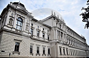 Facade, with statues, of a large and historic building, under the blue sky with small white clouds in Vienna.