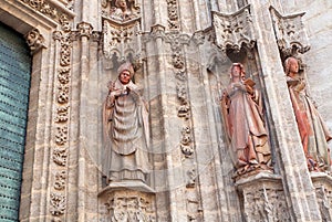 Facade with 16th century sculptures of Roman Catholic Seville Cathedral , Spain. Priest and women reading Bible