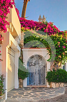 Facade of traditional Greek building with beautiful pink flowers. Turkey, Bodrum. Vintage old door with flowers