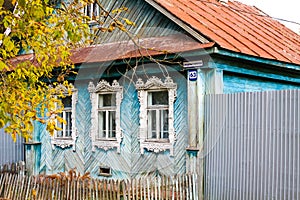 Facade of a traditional Russian wooden house izba with a red roof and blue walls in autumn