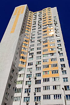 Facade of typical high rise apartment building with balcony and windows on blue sky background. Contemporary architecture.