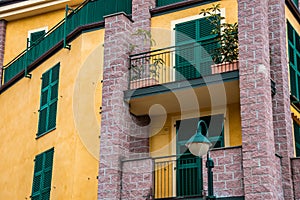 Facade of a typical residential apartment with colorful balcony and green window shutters in Italy, Liguria sea coast.