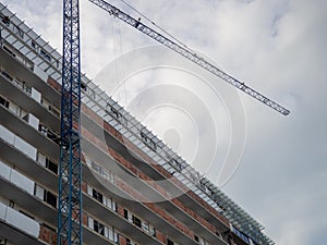 facade of an unfinished high-rise building. Construction crane near a panel house