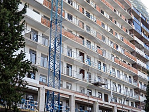 facade of an unfinished high-rise building. Construction crane near a panel house