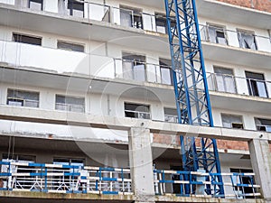 facade of an unfinished high-rise building. Construction crane near a panel house