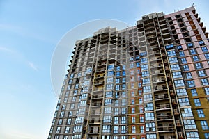 Facade of an unfinished high-rise residential building during construction on blue sky background. Skyscraper and tall house