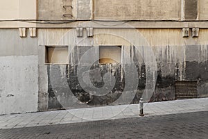 Facade of a very old building with granite ashlars, windows blocked with brick and cement and renovated stone floors photo