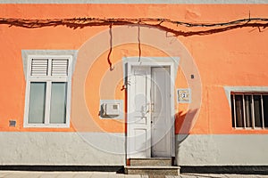 A facade of a vibrant orange house with a window and an open white front door in Galdar, Gran Canaria photo