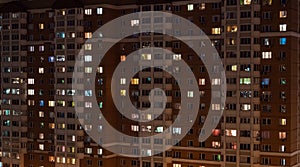 Facade view of living apartment building with glowing windows at night