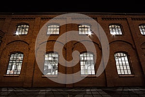 Facade of a vintage old red brick warehouse, used from an Industrial Revolution Era factory plant, with large windows