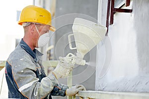 Facade work. Worker painting by spreading white paint