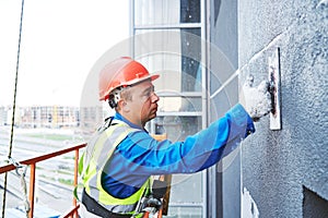 Facade worker plastering external wall of building