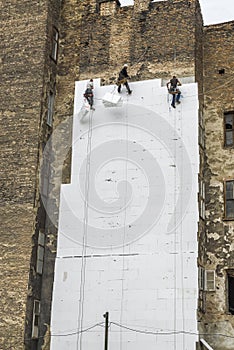 Facade workers mounting polystyrene insulation