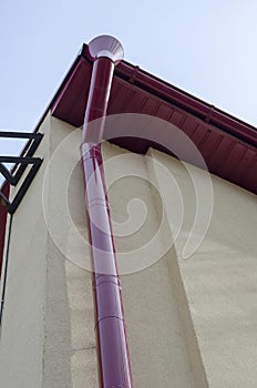 The facade of a yellow building with a red downpipe