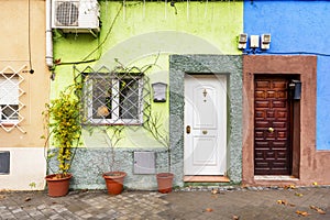 Facades of different decorative colors of two-story single-family homes with quarters Castilian wooden access doors and white