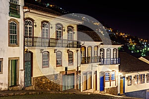 Facades of houses in colonial architecture on an old cobblestone street at night