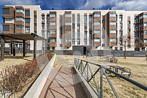 Facades of new buildings from a municipal park with wooden tables and benches