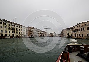 Facades of weathered buildings with windows on street of Venice city near canal water in daylight