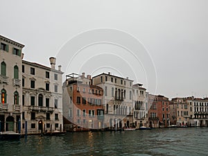 Facades of weathered buildings with windows on street of Venice city near canal water in daylight