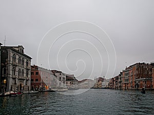 Facades of weathered buildings with windows on street of Venice city near canal water in daylight