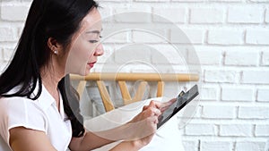 Face of 40s middle aged Asian woman holding credit card and mobile phone in cozy white room