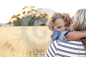 The face of an Adorable curly haired African American boy in the arms of his mother