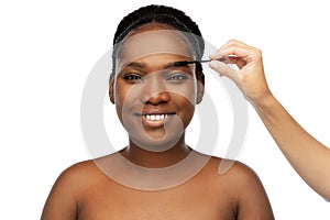 Face of african woman and hand with mascara brush