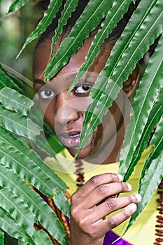 Face of african woman hid behind green leaves