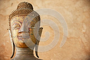 Face of an ancient copper Buddha statue outside of the Hor Phra Keo temple in Vientiane, Laos.