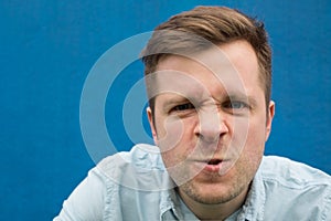 Face of an angry and furious caucasian man on a blue background.