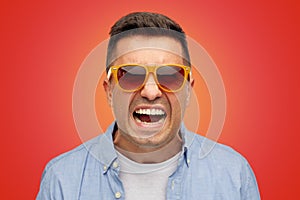 Face of angry man in shirt and sunglasses over red