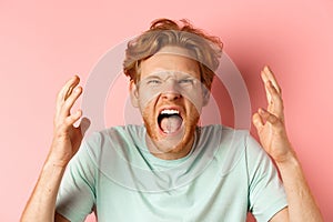 Face of angry redhead man shouting and shaking hands furious, staring outraged and cursing, express hatred and