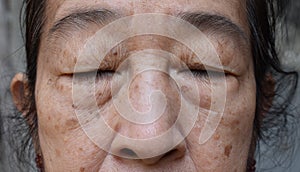 Face of Asian elder woman with closed eyes. Concept of aging photo