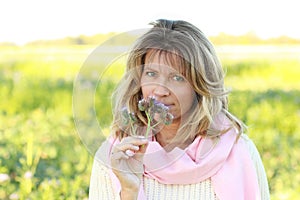 Face of an attactive mature woman sniffing on a lilac flower out