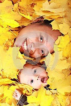 Face of baby boy and his mother under maple leaves