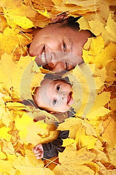 Face of baby boy and his mother under maple leaves