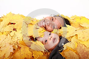 Face of baby boy and his mother under maple leaves