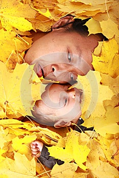 Face of baby boy and his mother under maple leaves