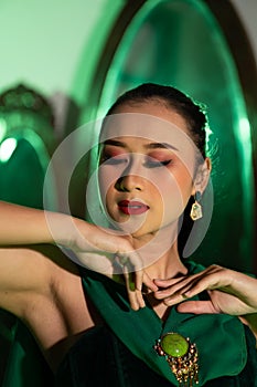 the face with beautiful makeup and red lips of an Asian woman in a green dress and jewelry